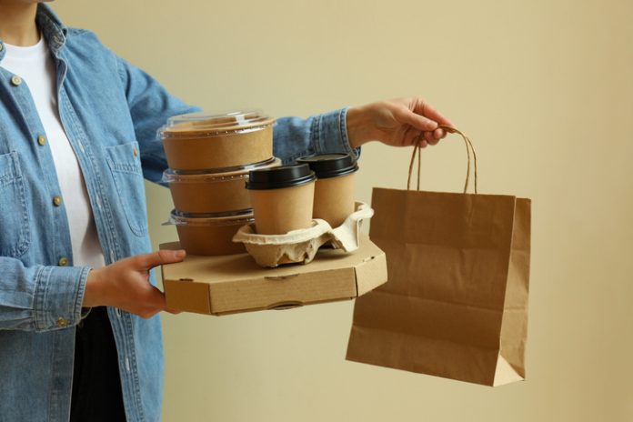 Une femme tient des conteneurs de livraison pour les plats à emporter sur fond beige emballage alimentaire