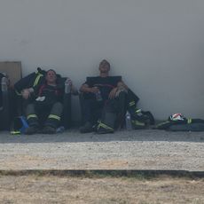 Des pompiers se reposent avec des bouteilles d'eau pendant les opérations de lutte contre un incendie de forêt près de Lanton, dans le sud-ouest de la France, le 29 juillet 2026